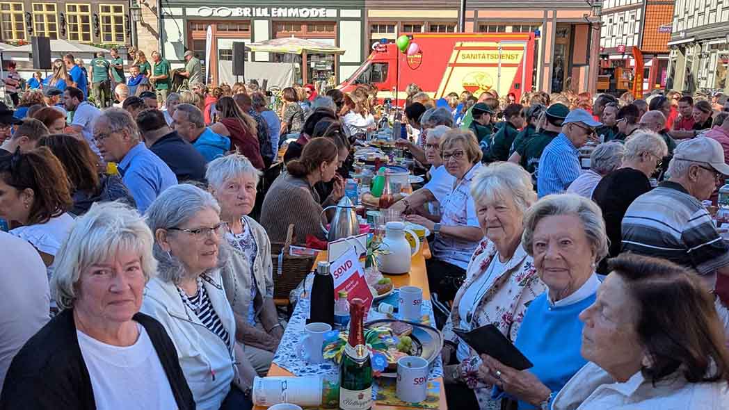Opern Air Tische an denen viele Menschen sitzen.