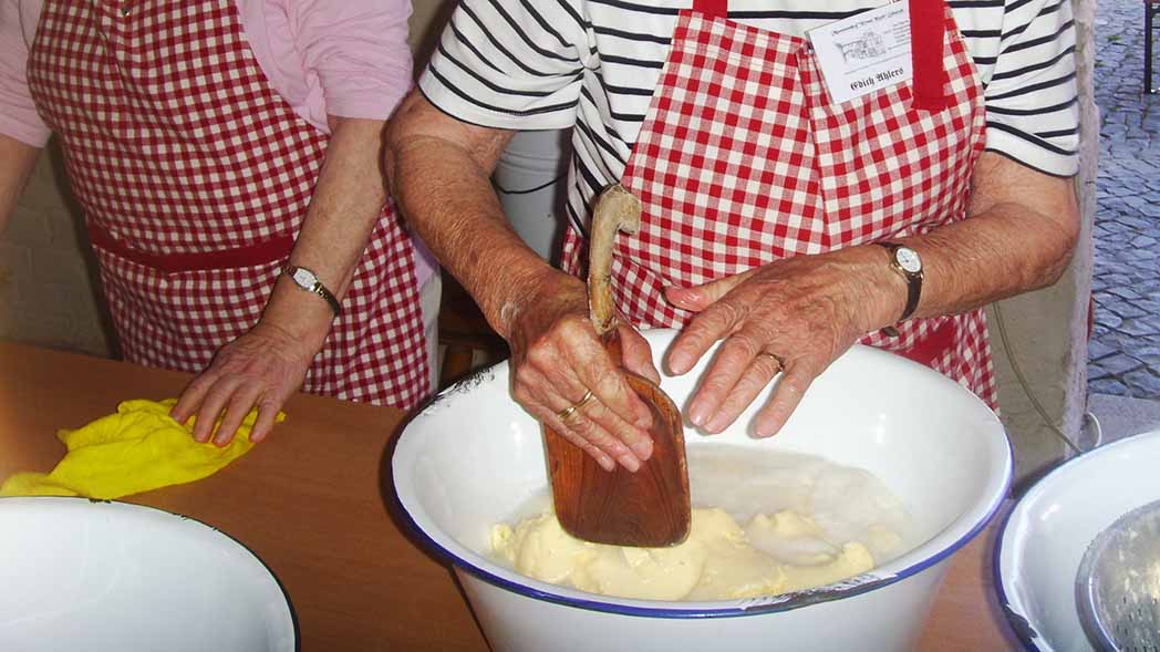 Hände von zwei Frauen beim Buttern.