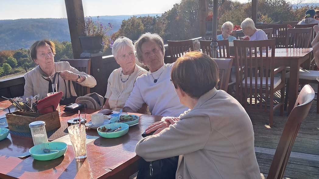 Vier Frauen sitzen auf Terrasse mit Blick auf die Landschaft